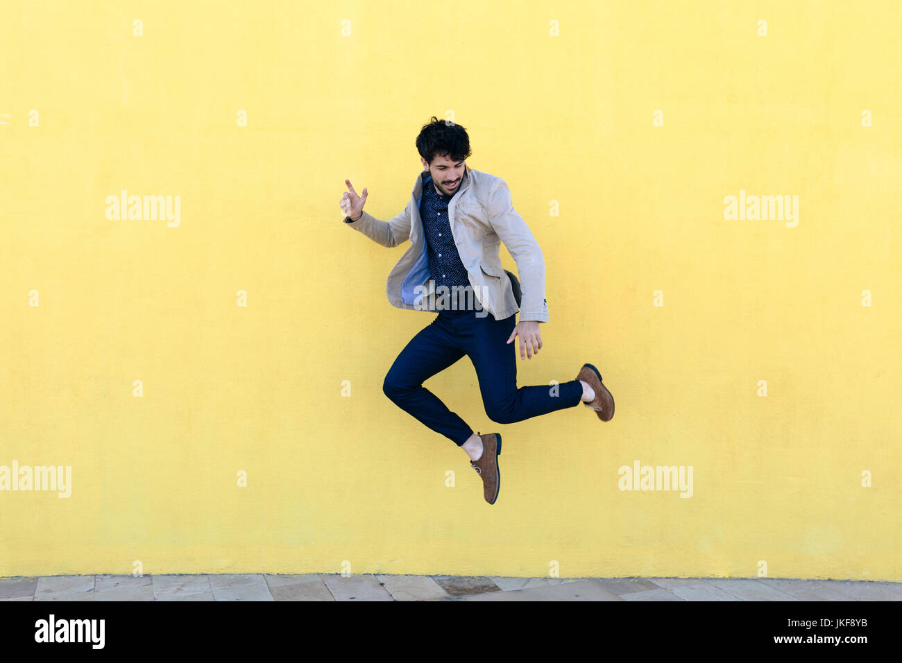 Junger Mann in die Luft vor der gelben Wand springen Stockfoto