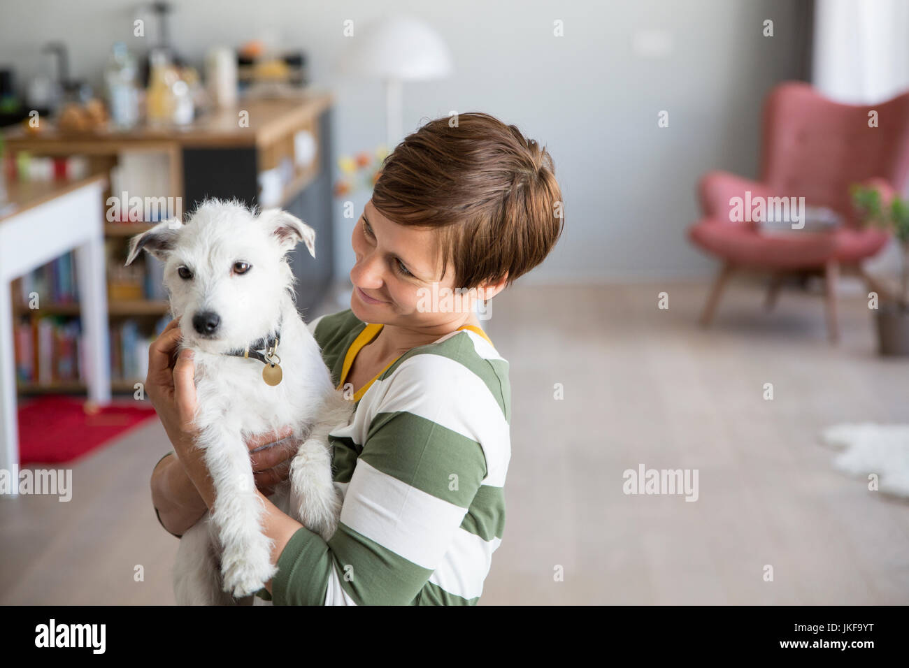 Frau mit Hund auf dem Arm zu Hause Stockfoto