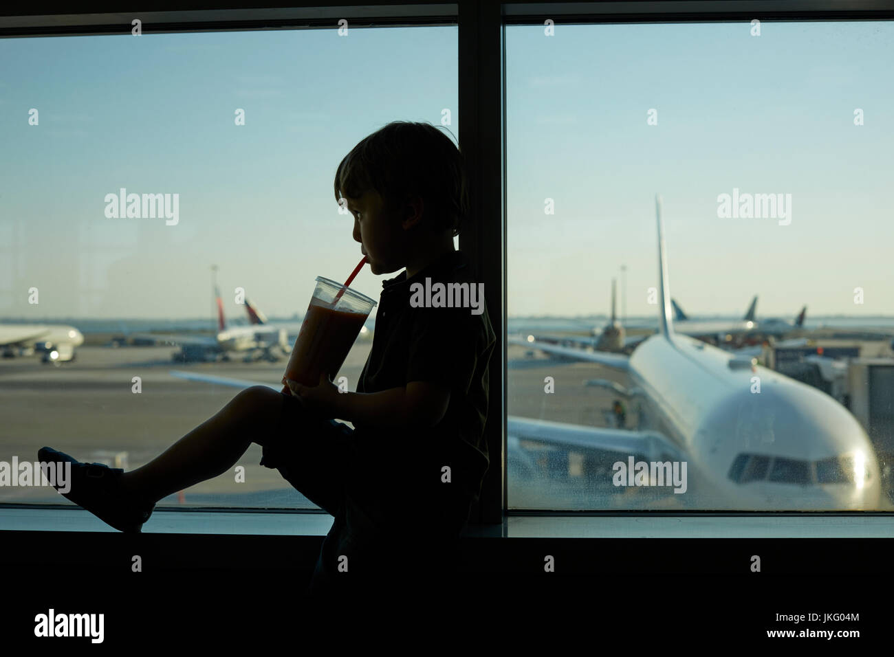 New York City, Vereinigte Staaten, JFK Airport Jungfrau ein kleiner Junge Passagier als die Getränke aus dem Fenster Stockfoto