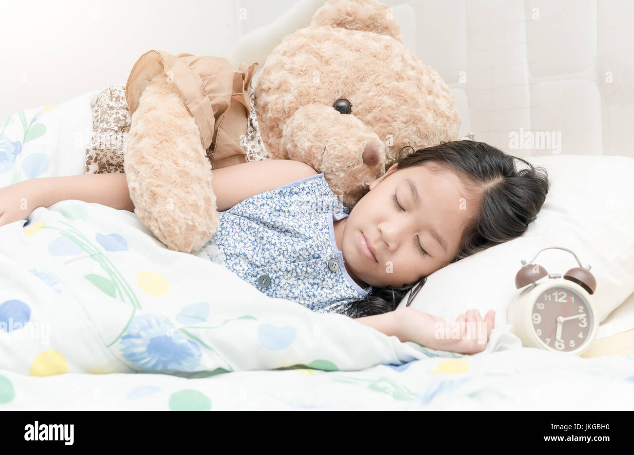 Entzückende kleine Mädchen schlafend im Bett mit ihr Teddy Bär Stockfoto