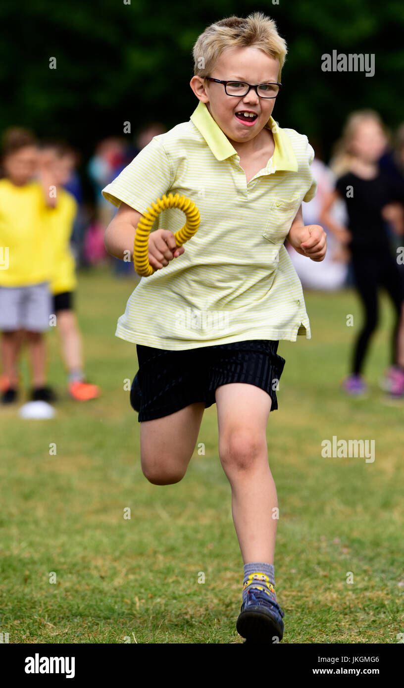 Sechs Jahre alter Junge Konkurrenz zu Relais Laufveranstaltung in einem Kindergarten Sporttag, Bordon, Hampshire, UK. 14. Juli 2017. Stockfoto