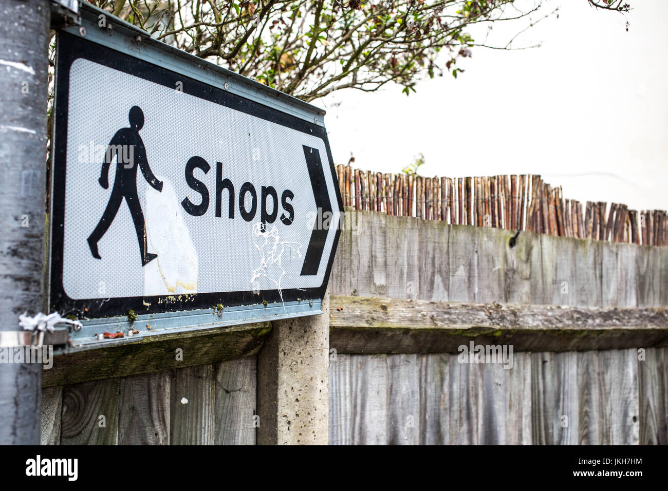 Öffentlichen oder Verkehrszeichen Regie Menschen zu den Geschäften gegen einen Holzzaun Stockfoto