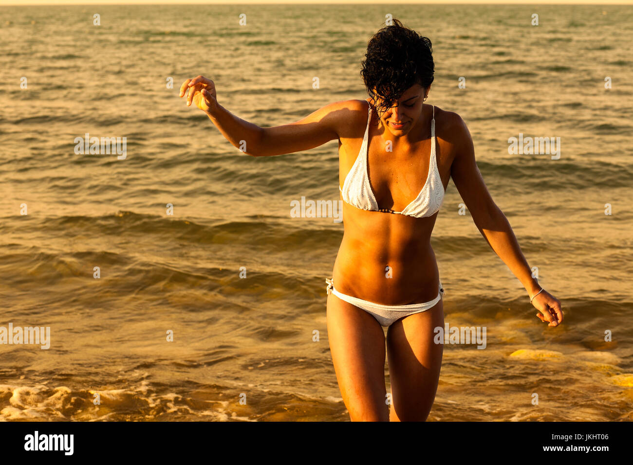 Frau am Strand zu Fuß in das Meer bei Sonnenuntergang Stockfoto