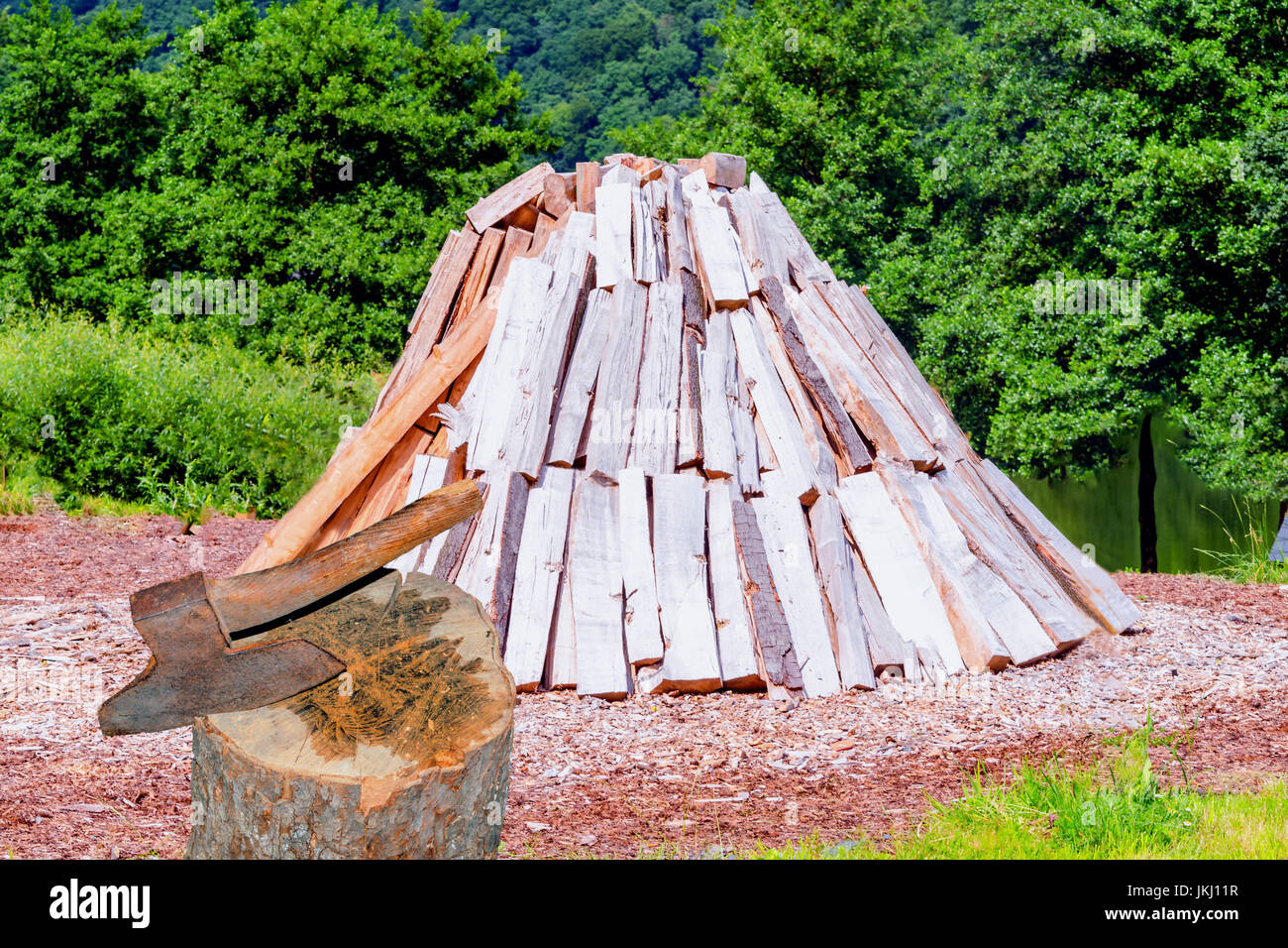 Konische gestapelten Protokolle, Lagerung von Brennholz für den Winter. Im Vordergrund ein Hack Holz mit Axt. Stockfoto