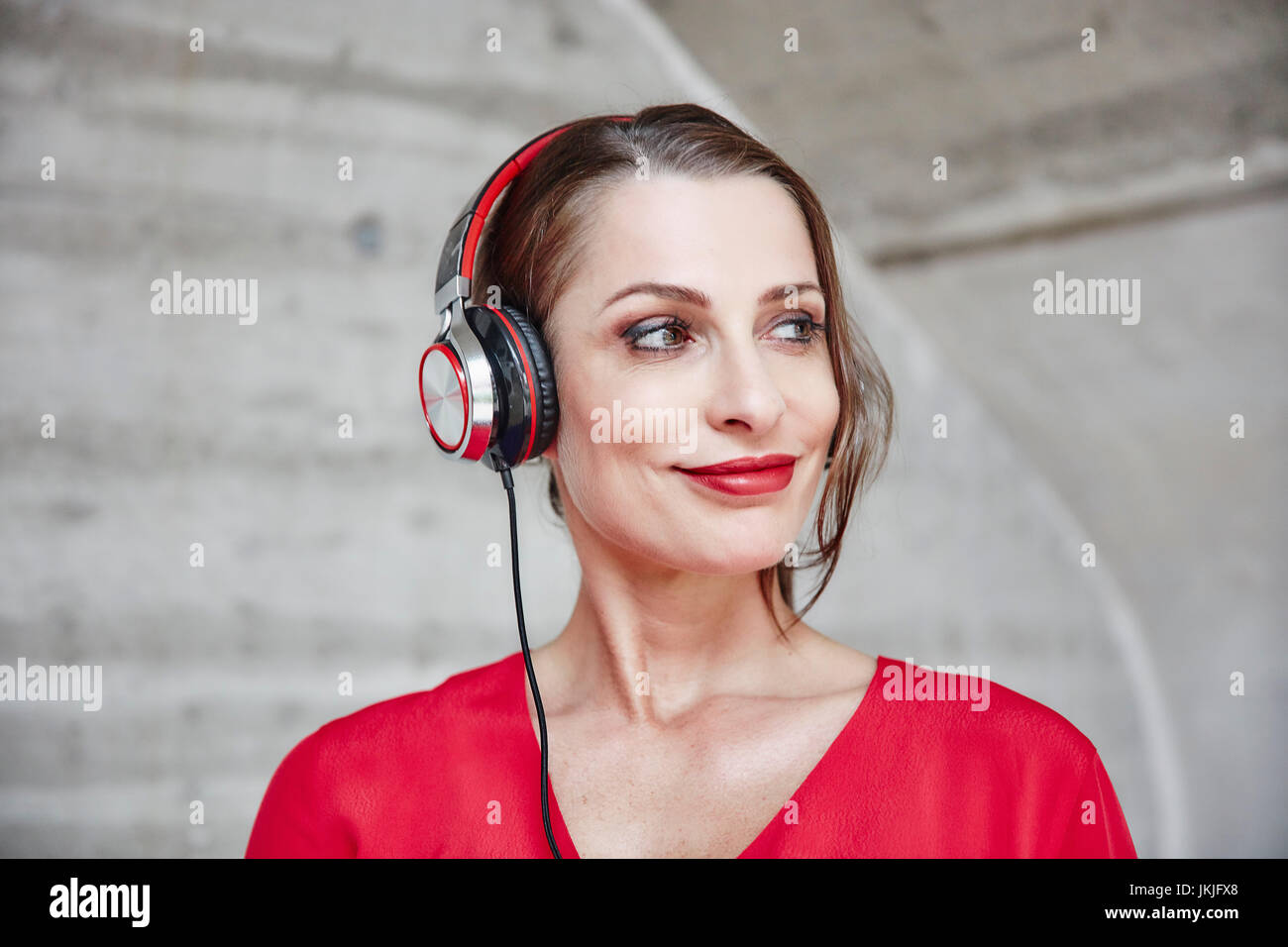 Lächelnde Frau Musikhören mit Kopfhörern Stockfoto