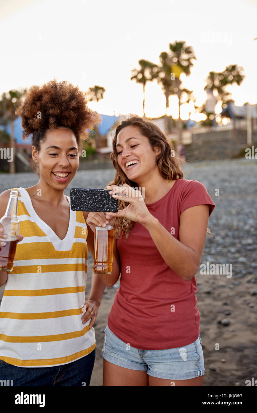 Zwei lachen Freunde mit Bierflaschen unter selfie am Strand Stockfoto