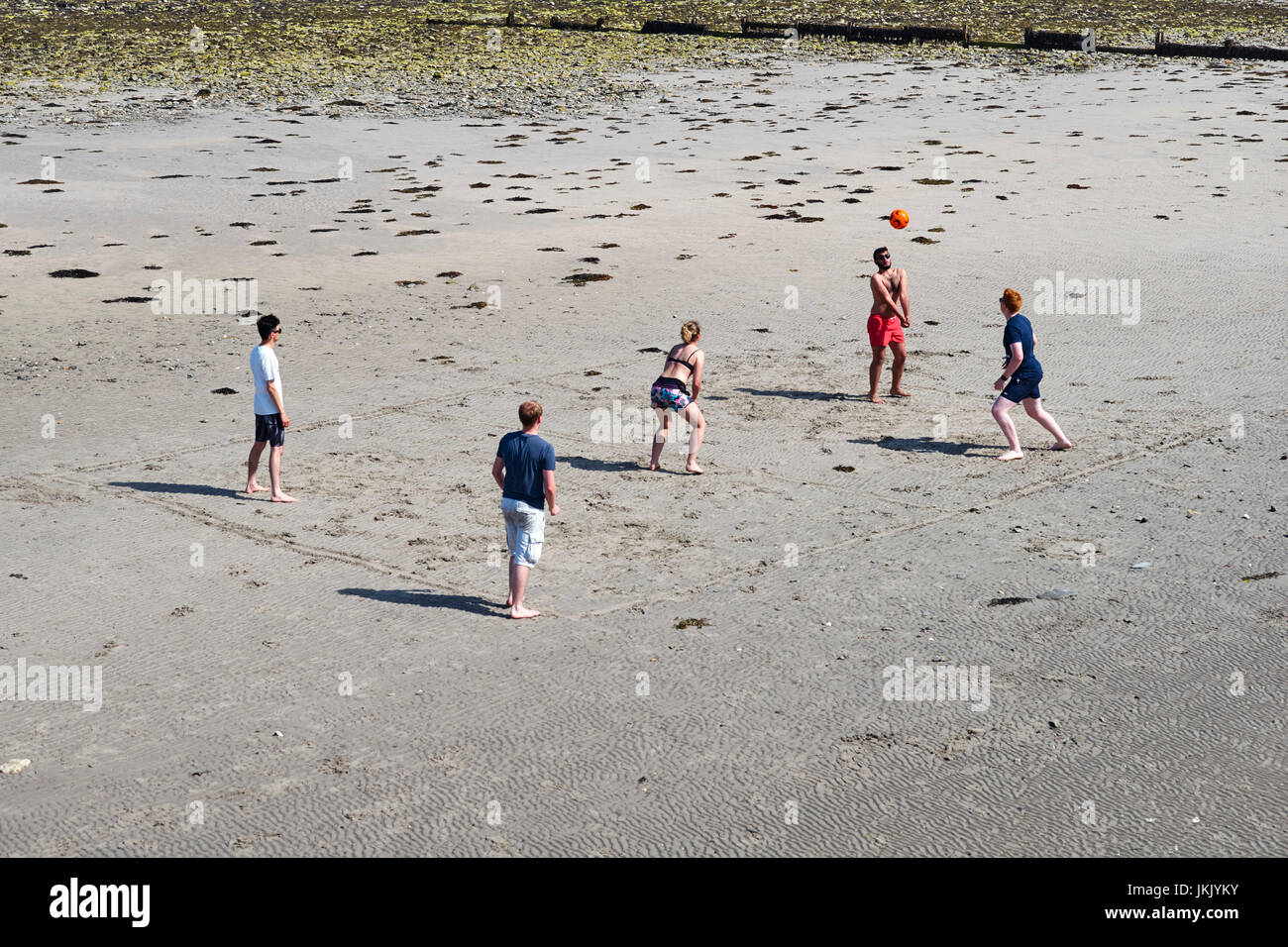 Fünf Personen spielen Volleyball am Strand von Douglas, Isle Of Man Stockfoto