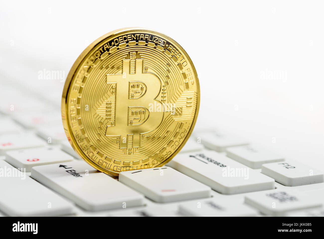Goldene Bitcoin auf weiße Tastatur auf weißem Hintergrund Stockfoto