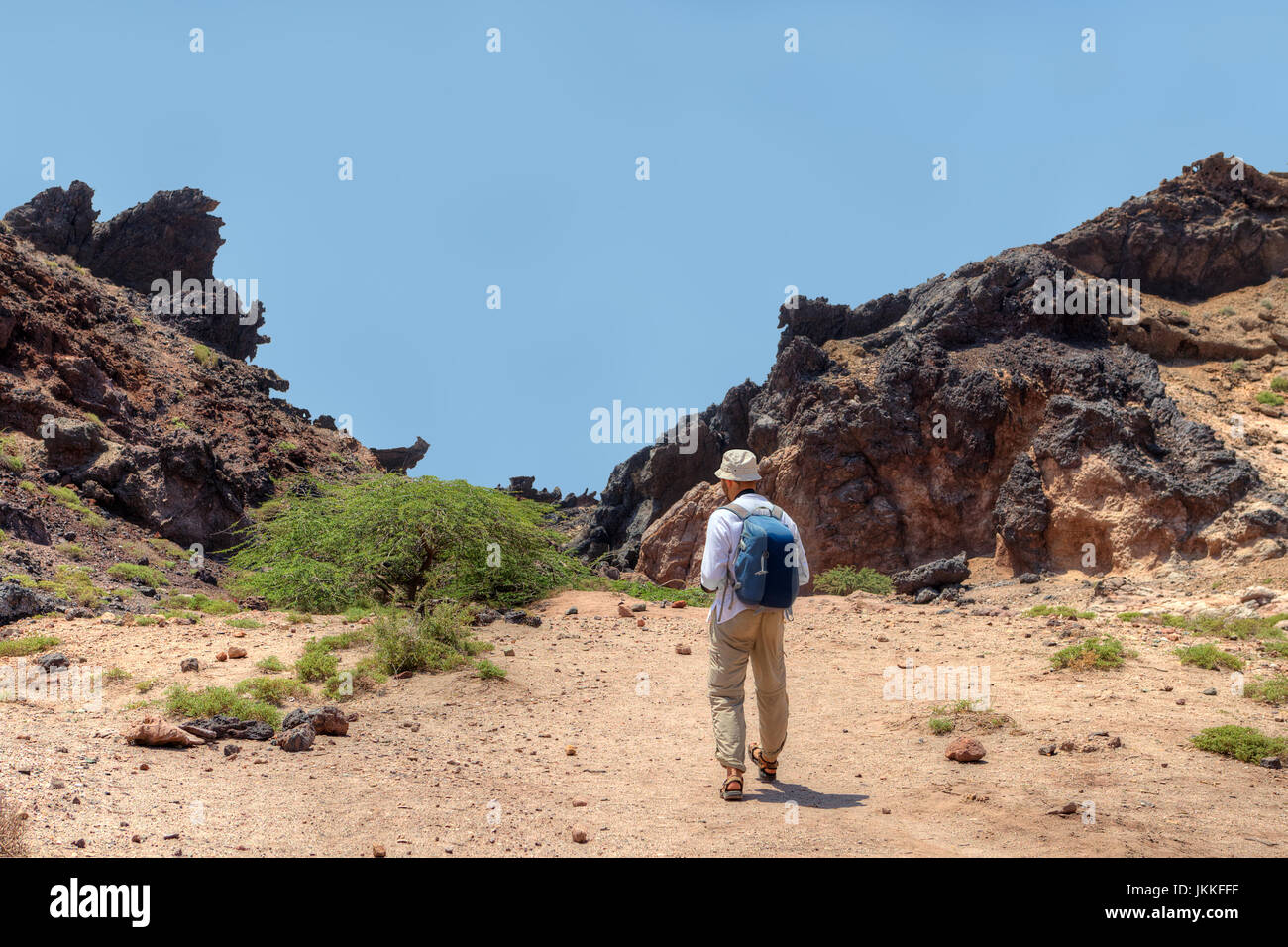 Blick von hinten auf den Touristen mit einem Rucksack, macht einen Spaziergang auf dem malerischen Orten, Hormus Insel, Provinz Hormozgan, Südiran. Stockfoto