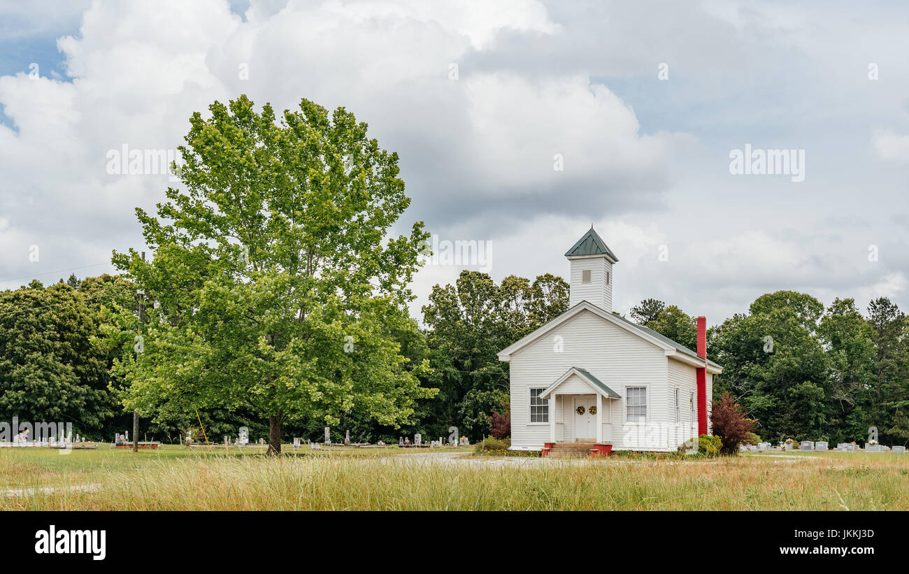 Kleine ländliche weiße Kirche und Friedhof auf einer Schotterstraße in ländlichen Alabama, USA. Stockfoto