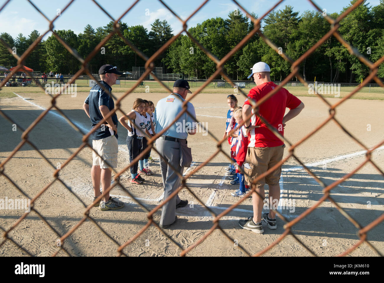 Trainer und Spieler sehen die Schiedsrichter-Münze zu Beginn des Mädchens Softball Spiel, New Hampshire State Turnier werfen Stockfoto