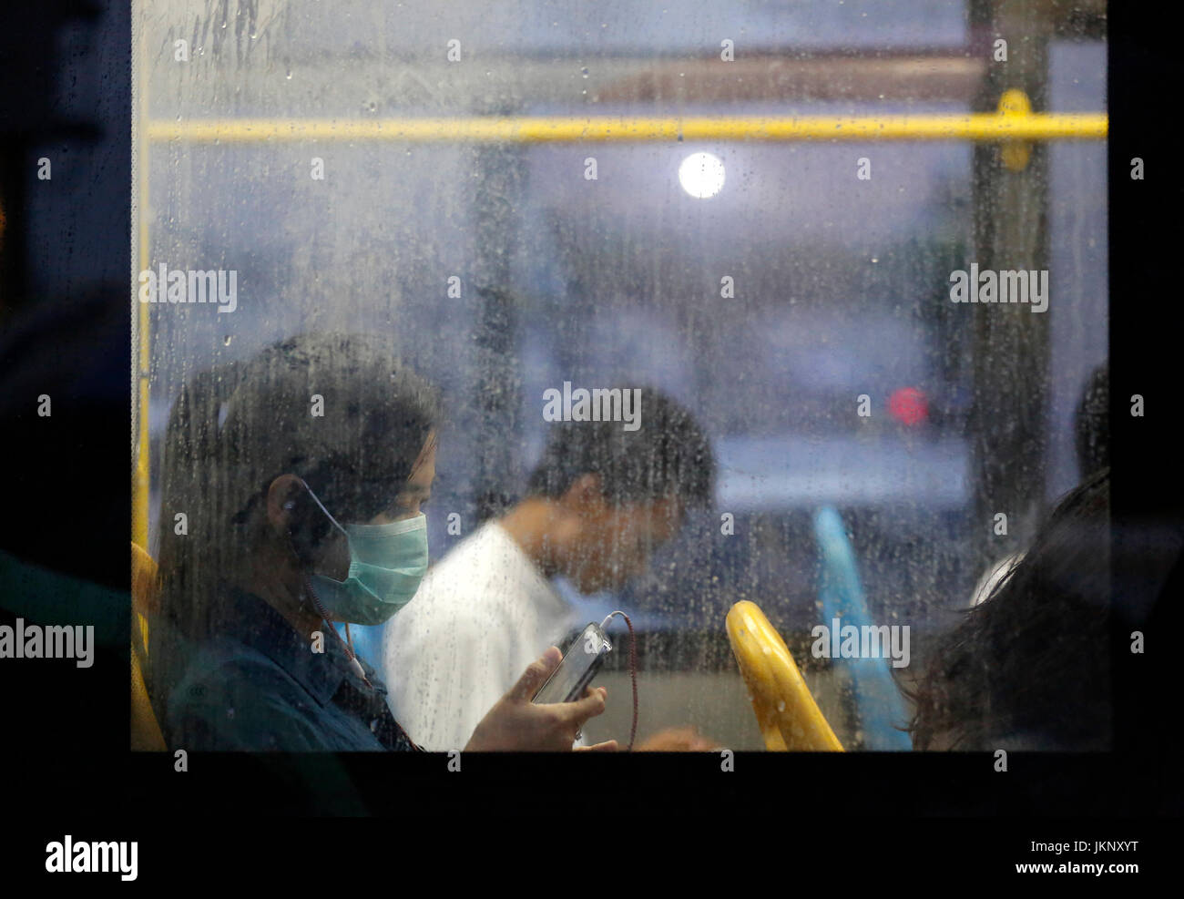 Yangon, Myanmar. 24. Juli 2017. Eine Mädchen trägt eine Maske nutzt ihr Handy in einem Bus in Yangon, Myanmar, 24. Juli 2017. Eine Person aus 13, infiziert mit saisonalen Grippe H1N1 2009 in Myanmar, ist nach einer Freigabe des Ministeriums für Gesundheit und Sport Montag gestorben. Bildnachweis: U Aung/Xinhua/Alamy Live-Nachrichten Stockfoto