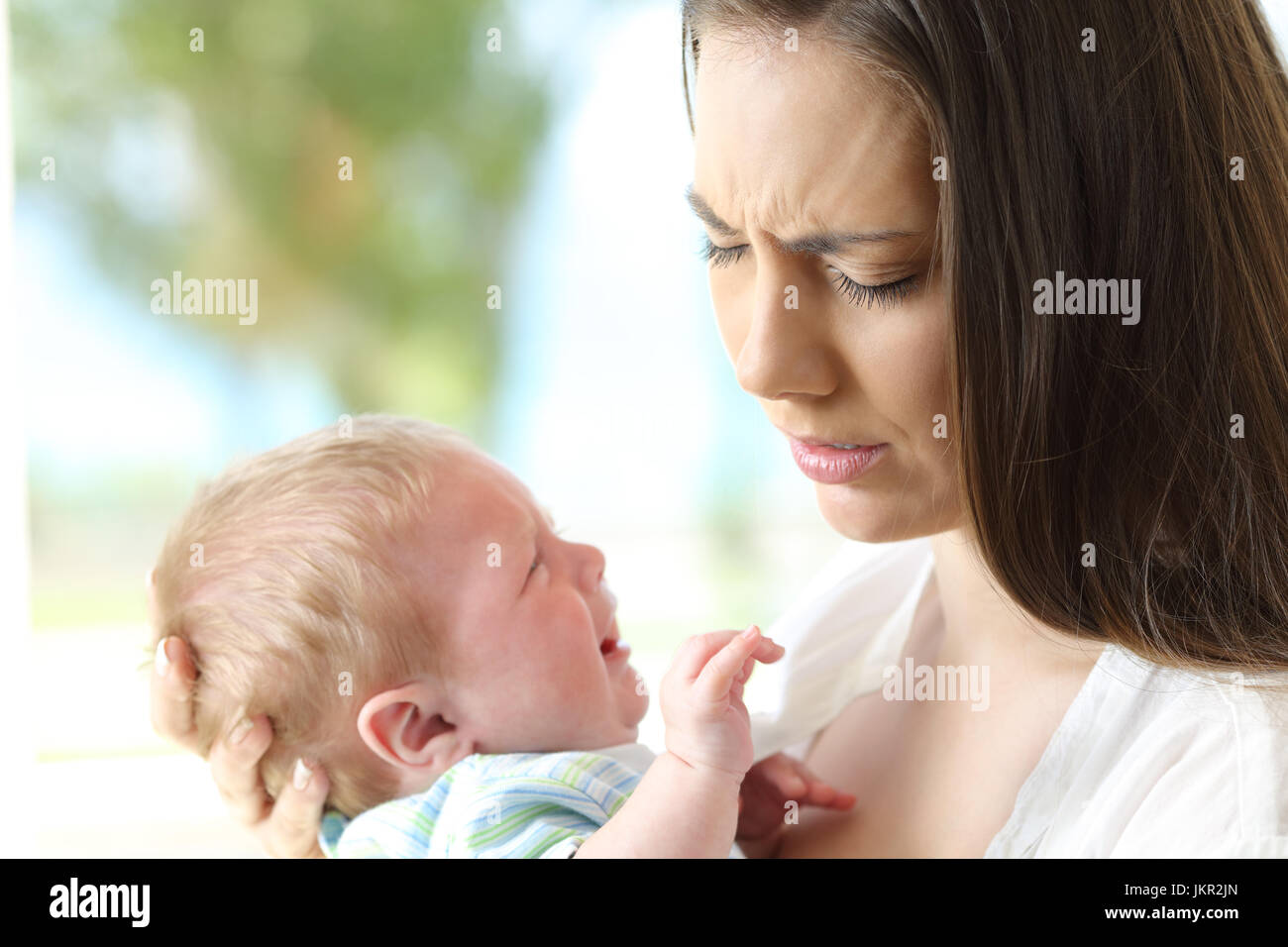 Erschöpfte verzweifelte Mutter hält ihr Baby weint Stockfoto