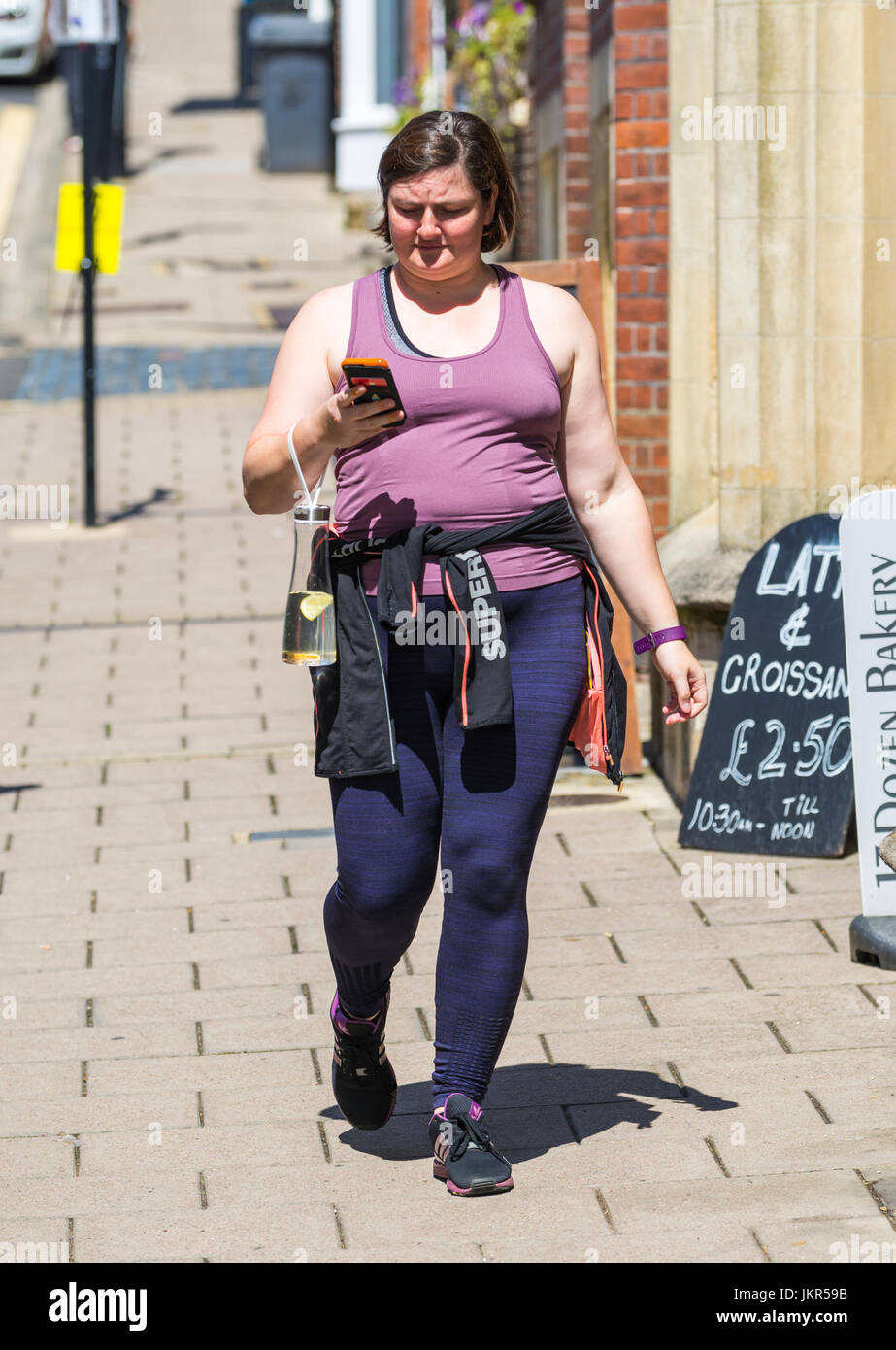 Junge Frau zu Fuß, während Ihr Smartphone suchen. Stockfoto