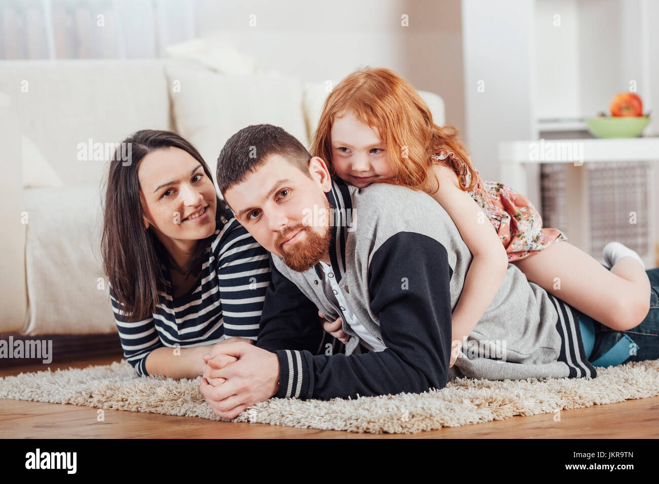 Porträt des Lächelns Familie liegen auf Teppich zu Hause Stockfoto