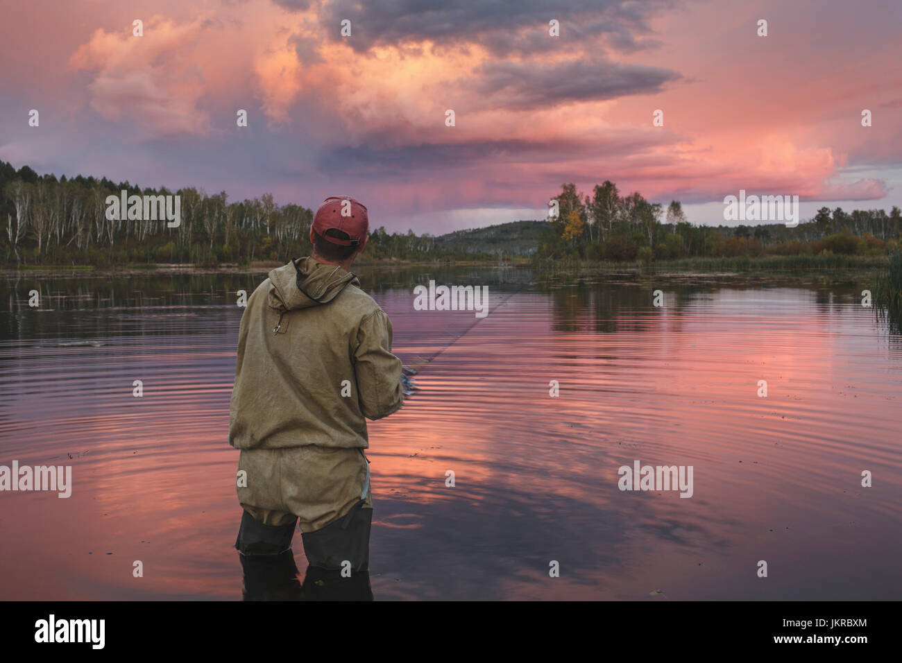 Rückansicht des Mann Angeln im See gegen bewölktem Himmel im Wald bei Sonnenuntergang, SWOBODNIJ, Amur, Russland Stockfoto