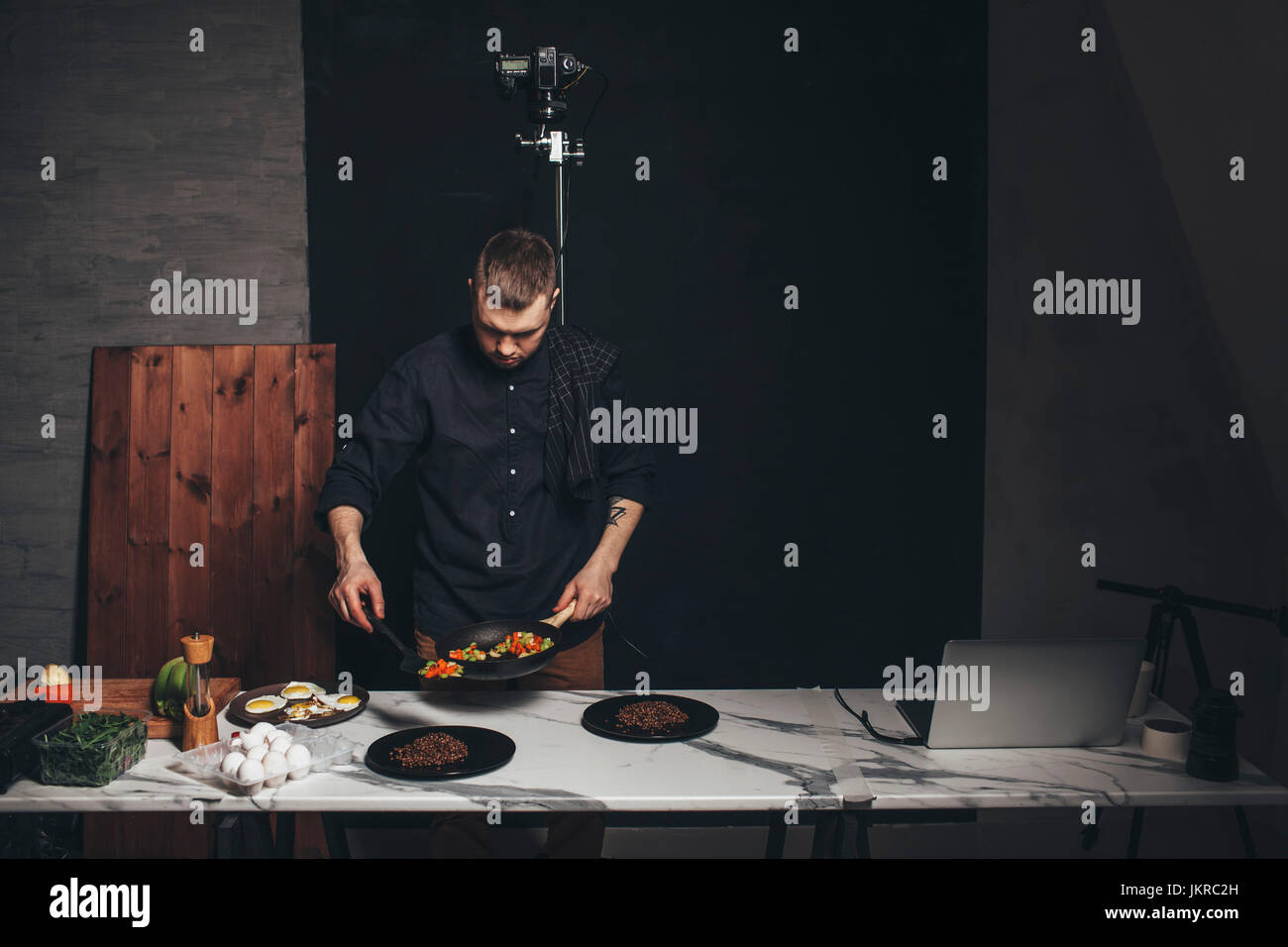 Koch, Vermittlung von Essen auf Marmor Zähler vor Hintergrund im studio Stockfoto