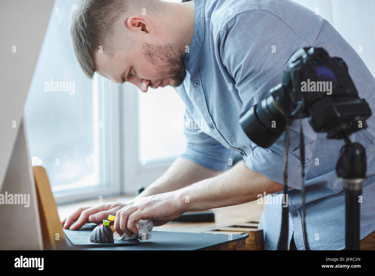 Mann Reinigung Essen Platte stehend mit Stativ-Kamera im studio Stockfoto