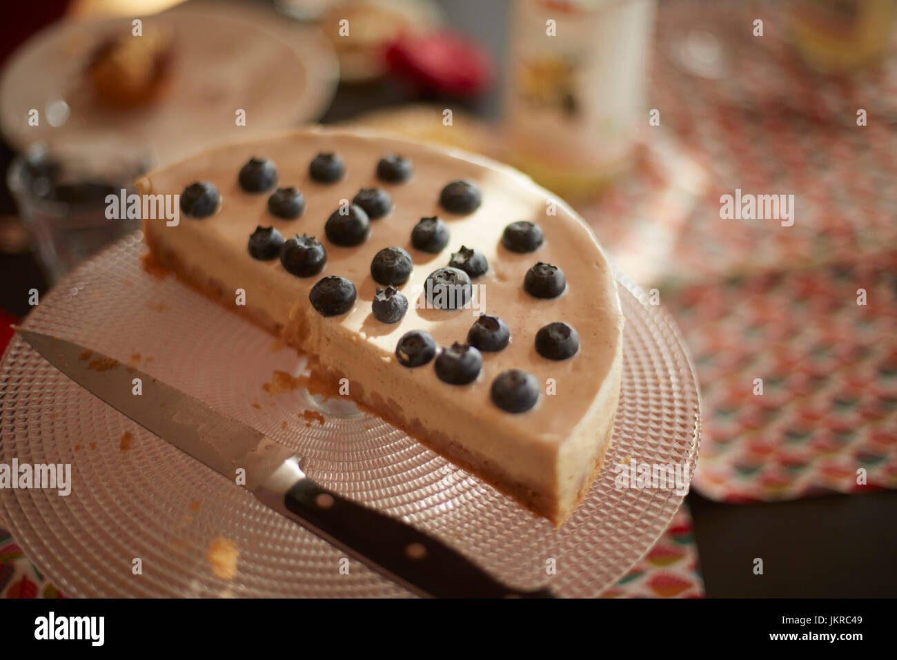 Erhöhte Ansicht der halbe Kuchen mit Küchenmesser auf Stand am Tisch Stockfoto