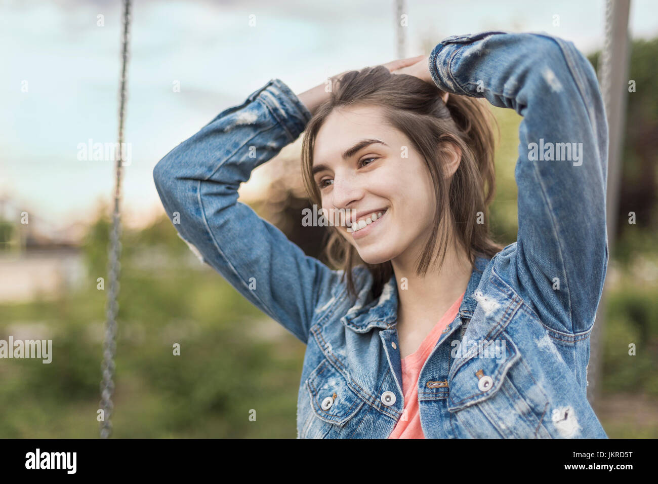 Lächelnde junge Frau mit Hand im Haar wegschauen im park Stockfoto