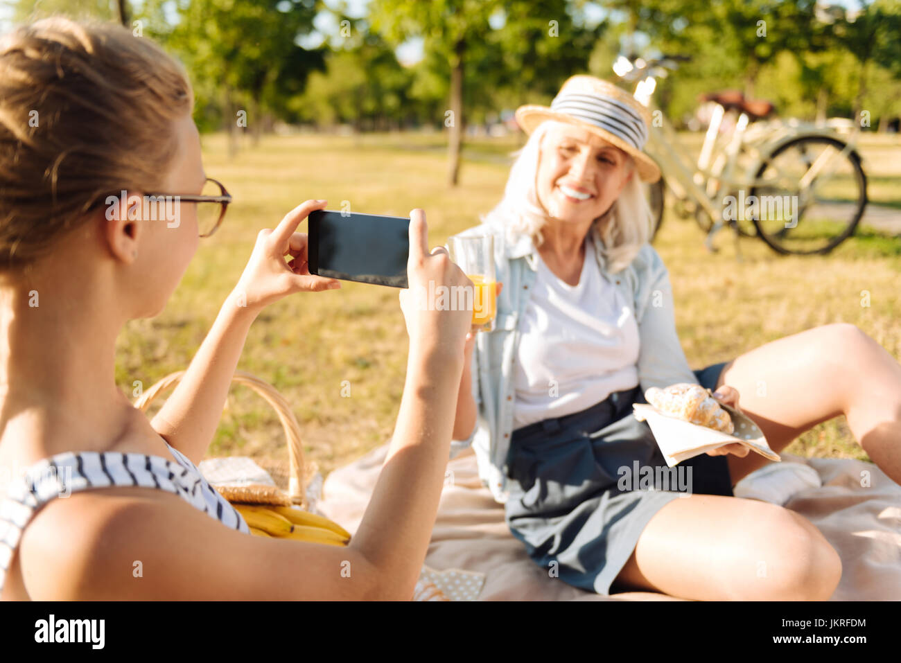 Angenehme Teenager-Mädchen, die Fotos von ihrer Großmutter ein Picknick Stockfoto