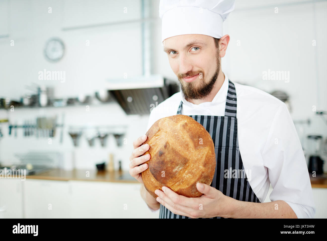 Bäcker in uniform, Holding runden Laib knuspriges Brot Stockfoto