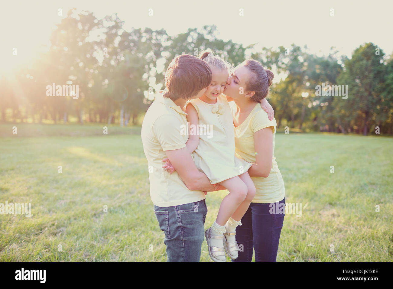 Arents küssen und umarmen ihre Tochter im Park. Stockfoto