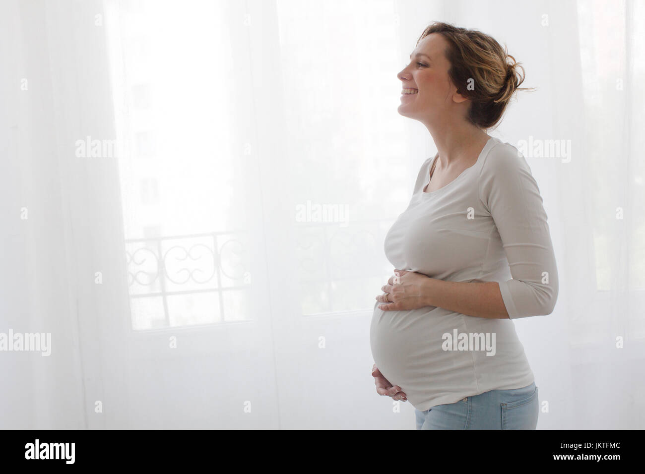 Schwangere Frau Bauch berühren und Lachen Stockfoto