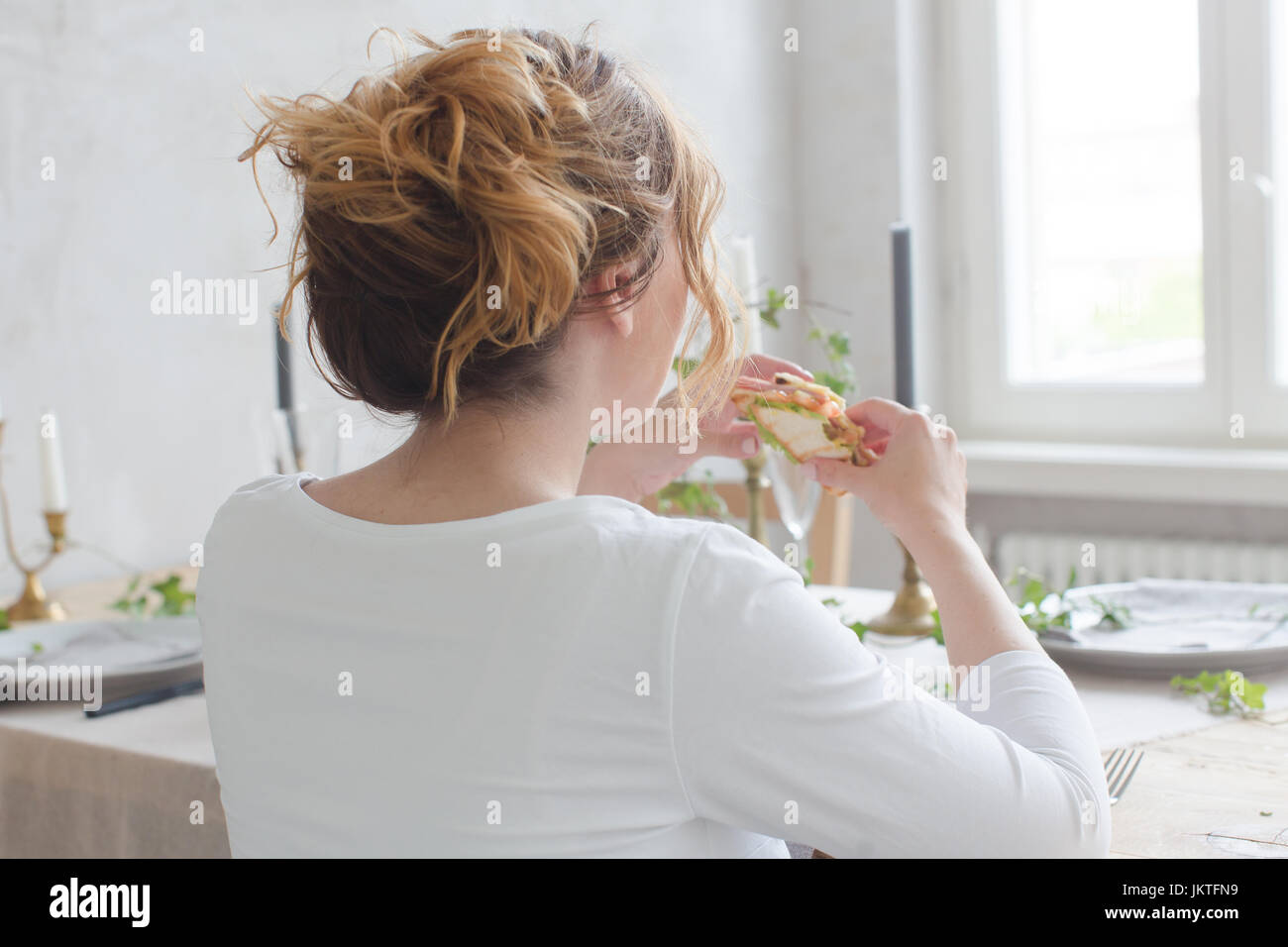 Frau am Tisch essen Sandwich sitzen Stockfoto