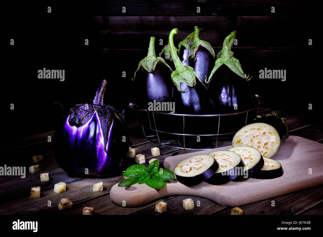 Nahaufnahme von frischem lila ganze Auberginen und geschnittene über ein alter Holztisch. Fotografiert mit leichten Maltechnik. Stockfoto