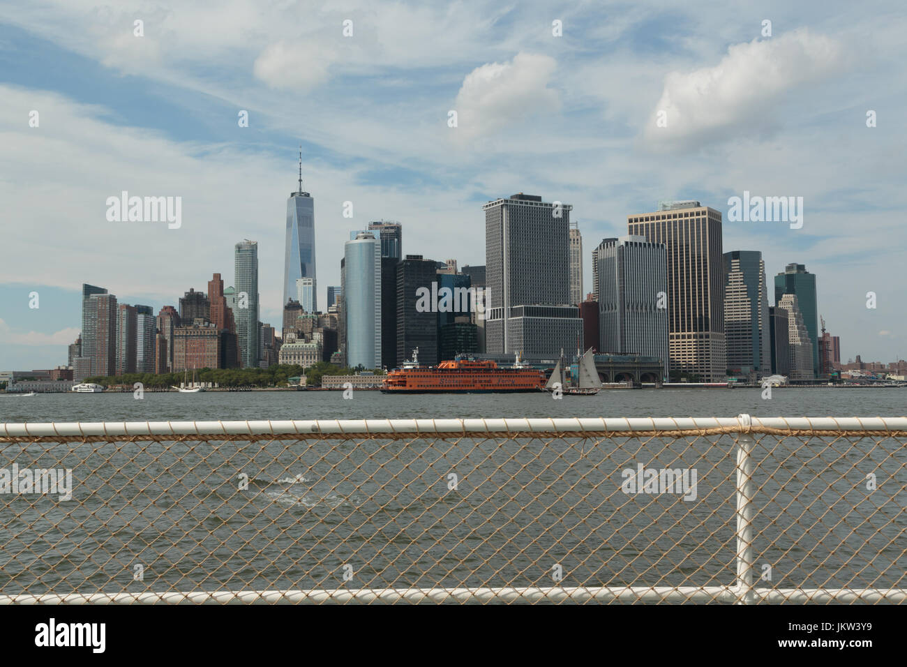 Ein Foto von der Skyline von Manhattan, wie von Governors Island, New York City zu sehen. Die berühmten orangefarbenen Staten Island Ferry und einem alten Segelschiff kann b Stockfoto