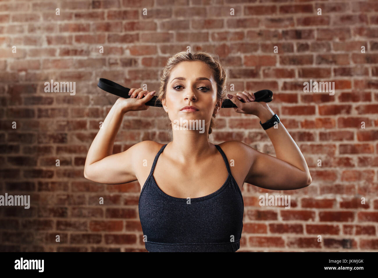 Sportlerin, die Ausübung der holding ein Übungsband hinter ihrem Kopf. Nahaufnahme der jungen Sportlerin drinnen trainieren. Stockfoto