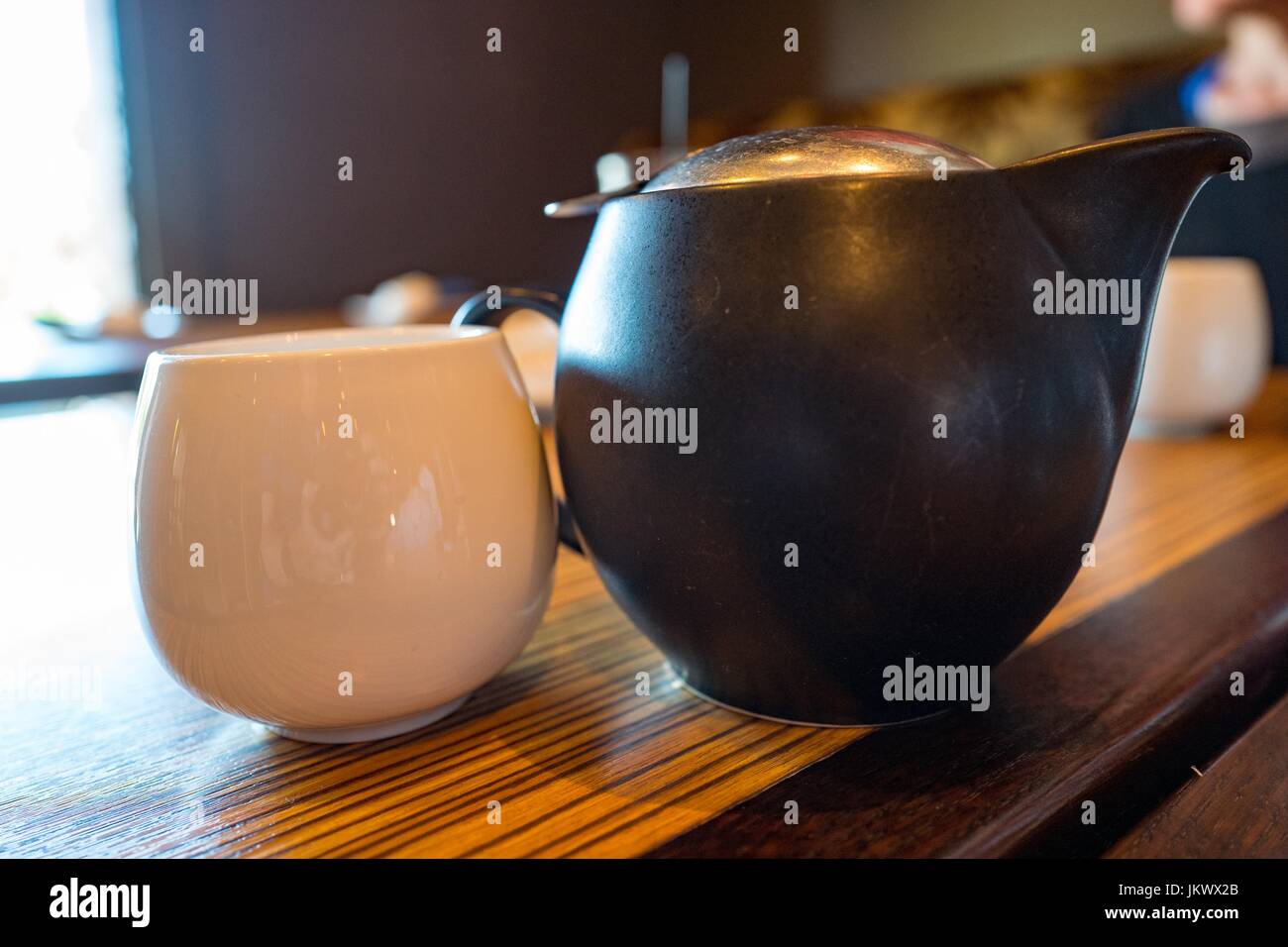 Nahaufnahme einer Tasse grünem Tee neben einem Teekessel auf einem Holztisch, 18. Juli 2017. Stockfoto