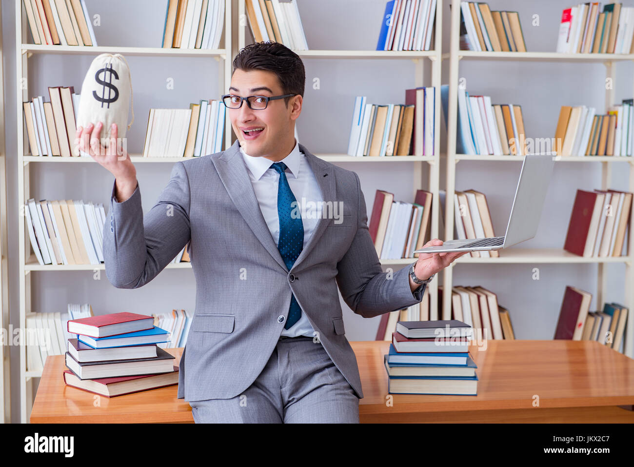 Geschäftsmann in Bibliothek mit meschotschek Geld und laptop Stockfoto