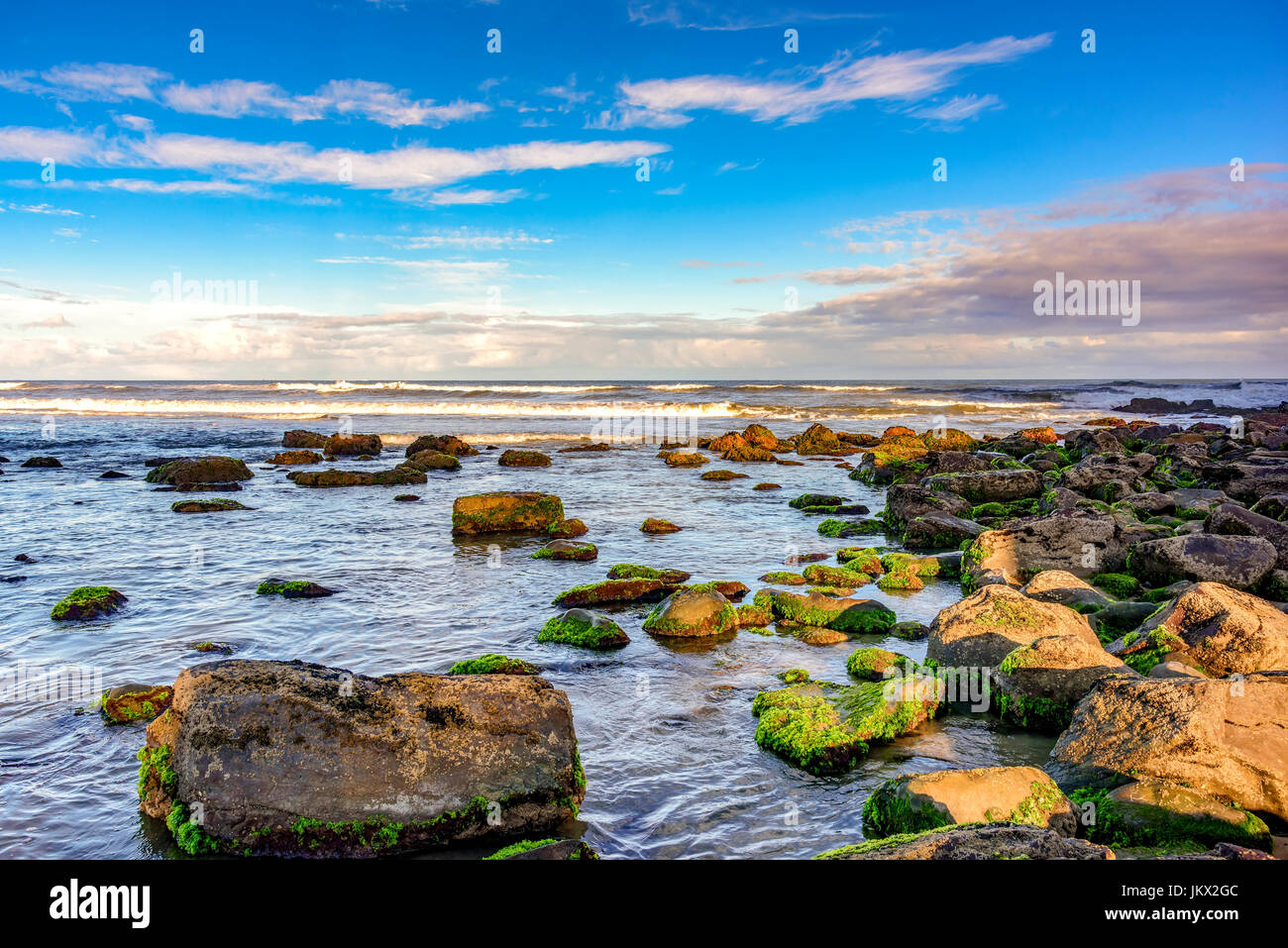 Bemoosten Steinen und Wellen zwischen den Gewässern des Cal Beach in Torres-Stadt, Rio Grande do Sul Stockfoto