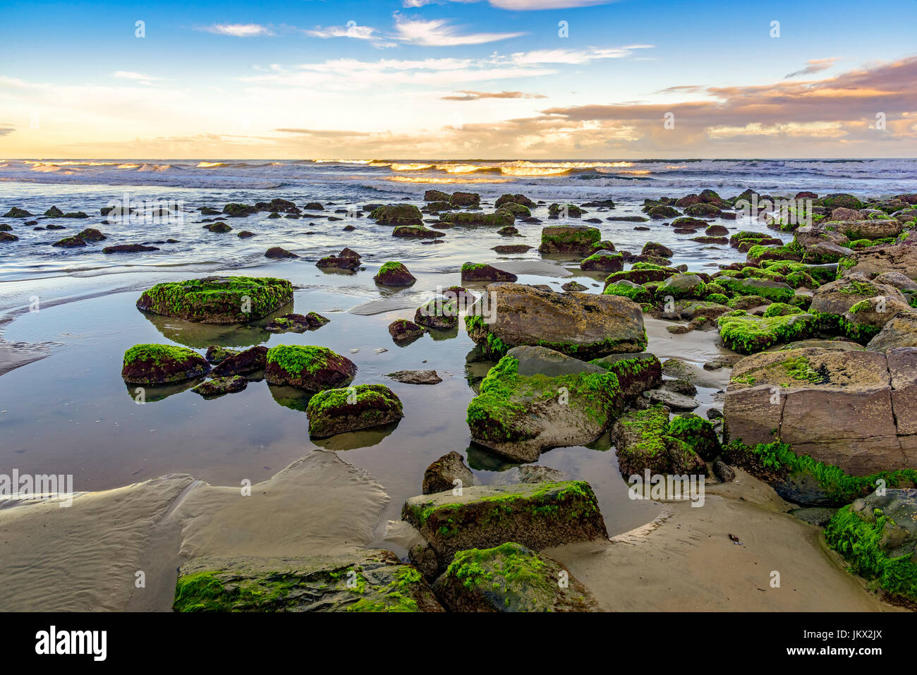 Bemoosten Steinen und Wellen zwischen den Gewässern des Cal Beach in Torres-Stadt, Rio Grande do Sul Stockfoto