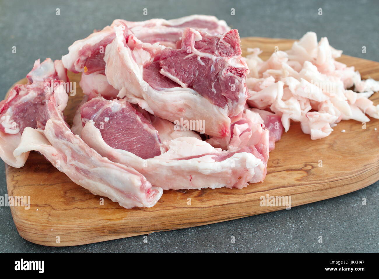 ChopRaw Lamm Lammkoteletts und Fett auf Oliven Holz Schneidebrett abstrakt grau unterlegt. Gesund kochen-Konzept. Stockfoto