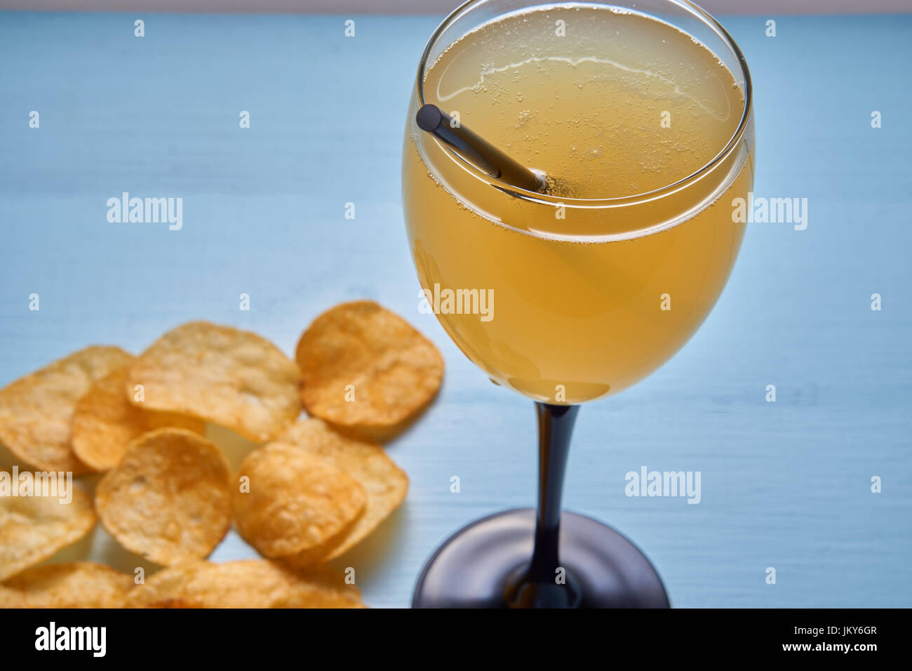 Nahaufnahme des goldenen gemixten Drink schütteln mit Stroh und unscharfen Kartoffelchips auf Hintergrund. Glas mit Getränk im Fokus Stockfoto