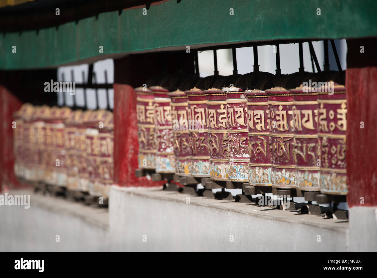 Heiligen tibetischen Gebetsmühlen ordnen in Zeile für Personen, die Rollen im Tempel Stockfoto