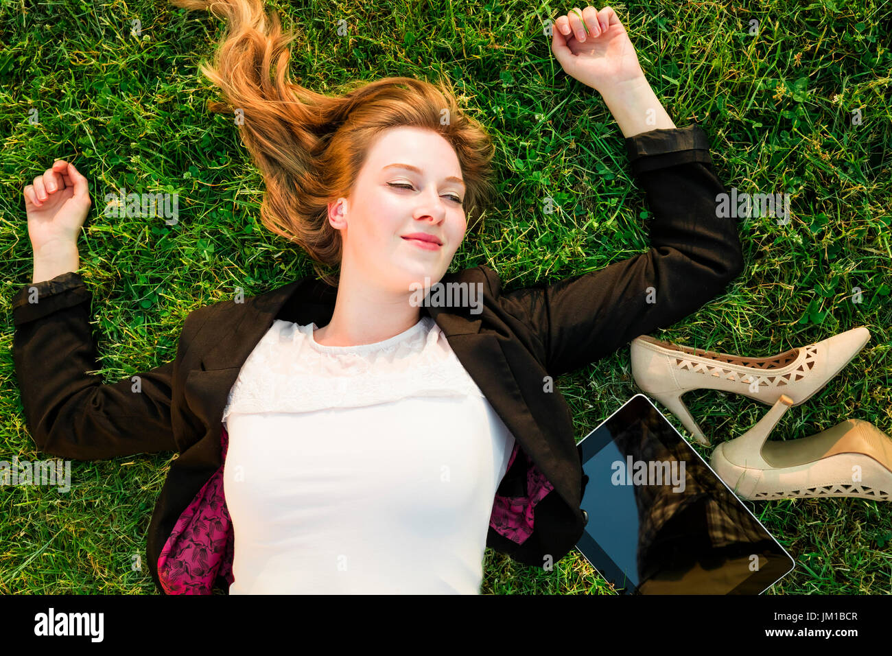 junge unabhängige Frau entspannen auf dem Rasen im park Stockfoto