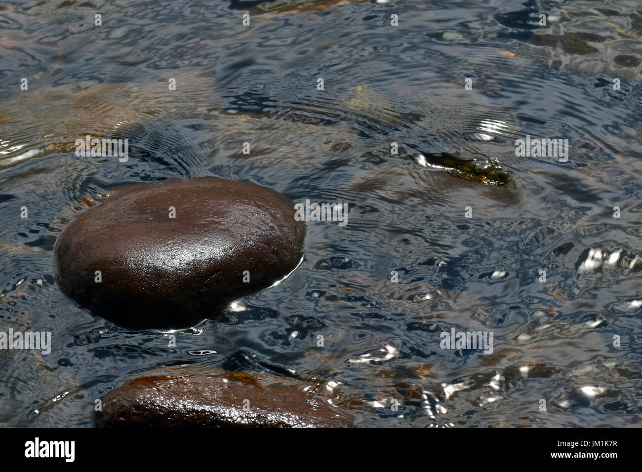 Steinen im Wasser. Eine schöne nasse polierter Stein oberhalb der Wasseroberfläche. Stockfoto