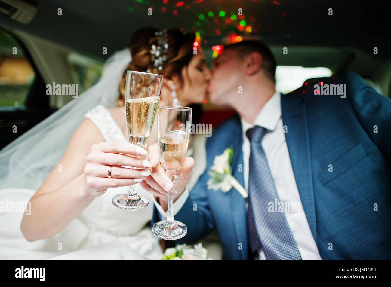 Frisch verheiratetes Paar trinken Champagner in der Limousine am Tag ihrer Hochzeit. Stockfoto