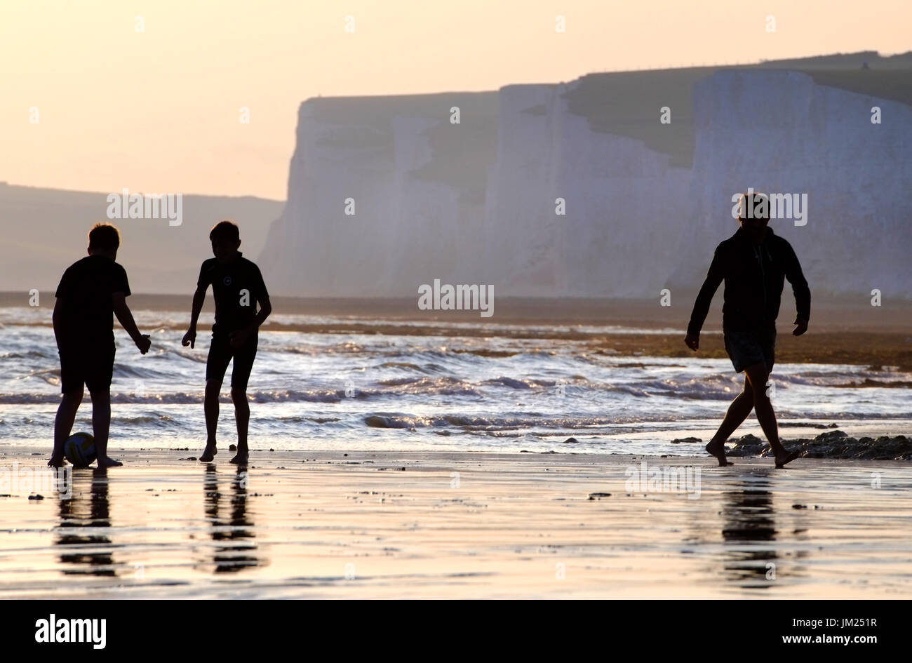 Familie genießen Beach-Fußball in der untergehenden Sonne, Birling Gap, East Sussex, UK Stockfoto