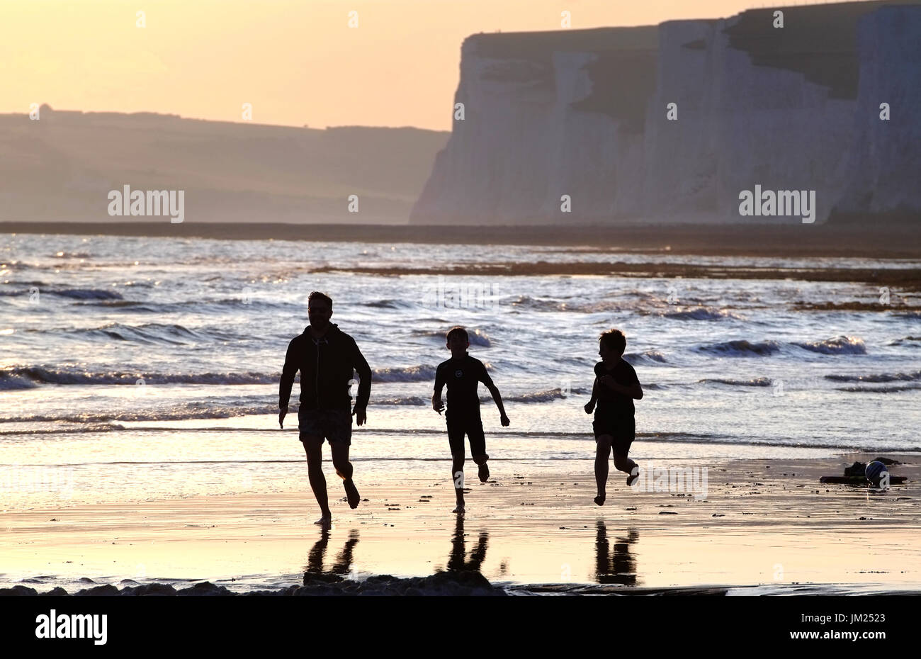 Familie genießen Beach-Fußball in der untergehenden Sonne, Birling Gap, East Sussex, UK Stockfoto