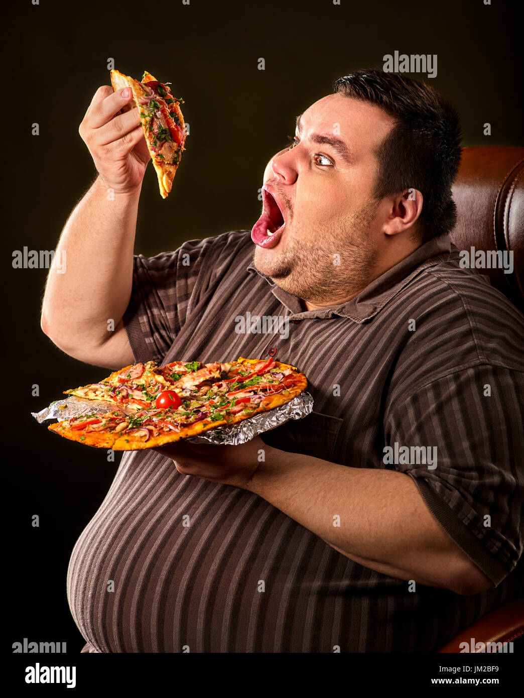 Dicker Mann essen Fastfood Stück Pizza. Frühstück für übergewichtige. Stockfoto