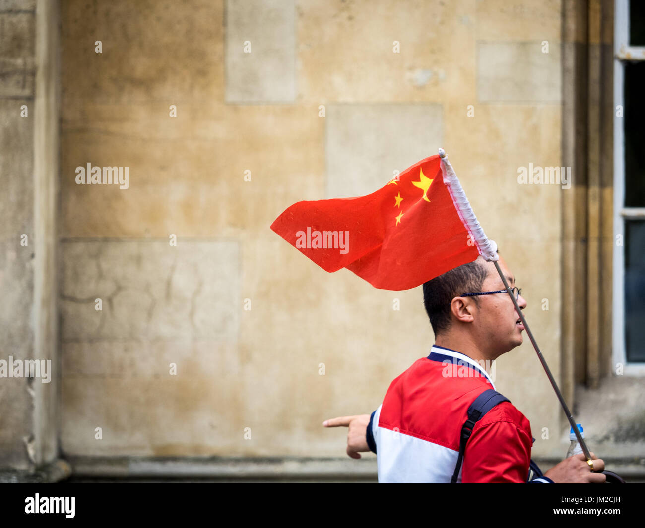 Chinesische Touristen Cambridge - spricht ein Tour Guide Identifikation Flagge mit seiner Reisegruppe im historischen Zentrum der Cambrdige UK Stockfoto