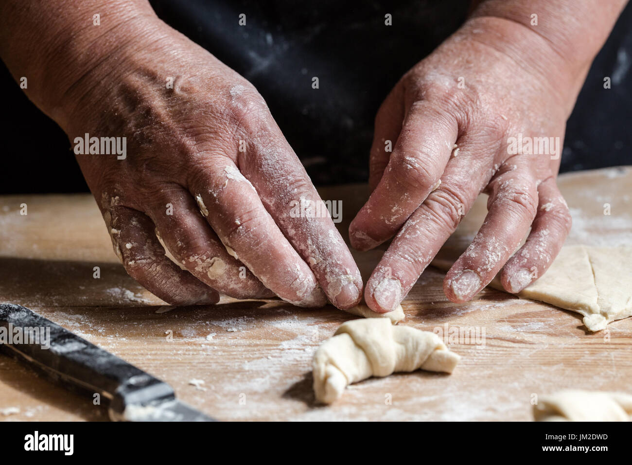 Ältere Frau, Oma, rollenden frische hausgemachte Croissants. Vertikale Ausrichtung. Hautnah auf funktionierende alte Hasen. Gesättigte, gedämpften Farben Stockfoto
