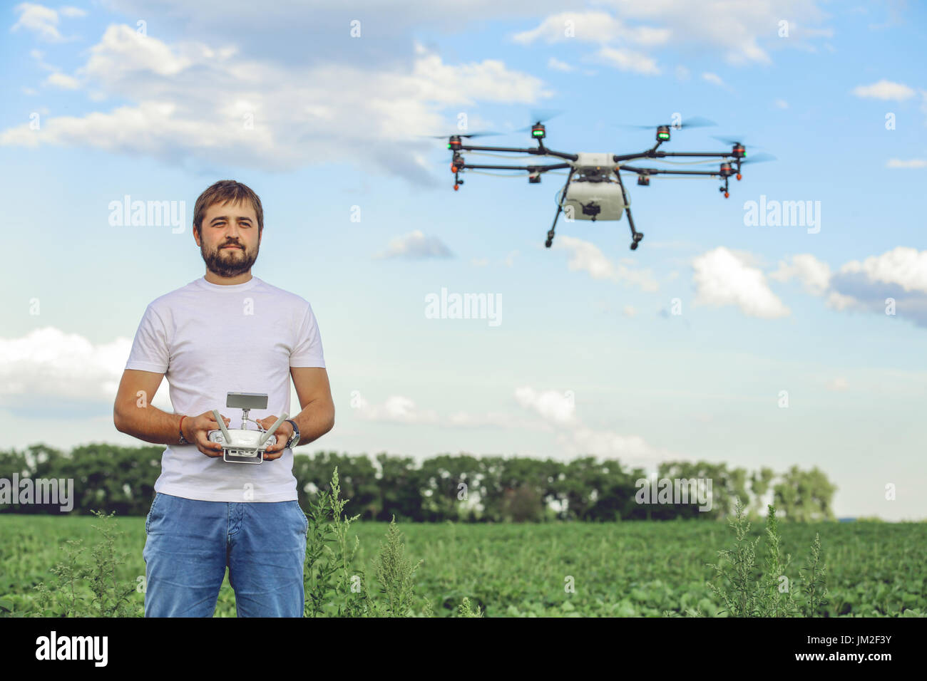 Porträt eines jungen männlichen Bauern mit einer professionellen Drohne gegen ein grünes Feld Stockfoto