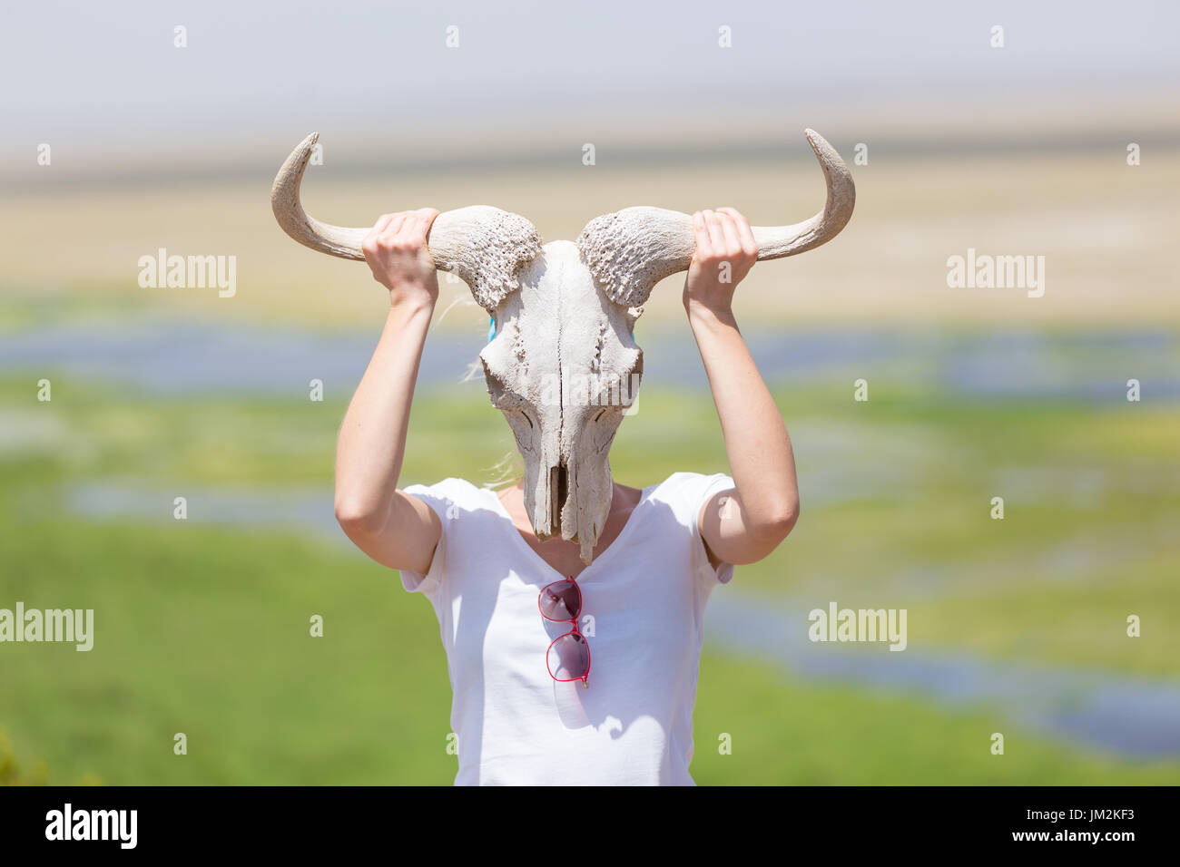 Frau mit einem weißen Gnus Schädel trägt es wie eine Maske in der Natur auf afrikanischen Safari. Stockfoto