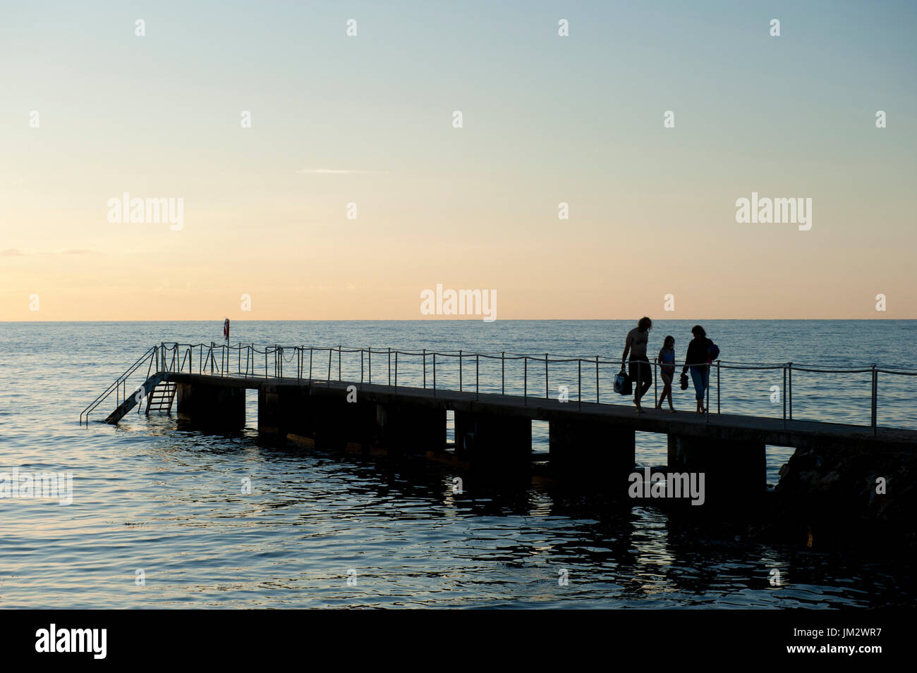 Ein Kind-Schwimmer geht neben ihren Eltern auf einem Pier in Torekov, Schweden Stockfoto